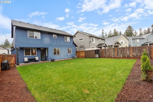 back of property featuring central air condition unit, a patio area, a yard, and a shed