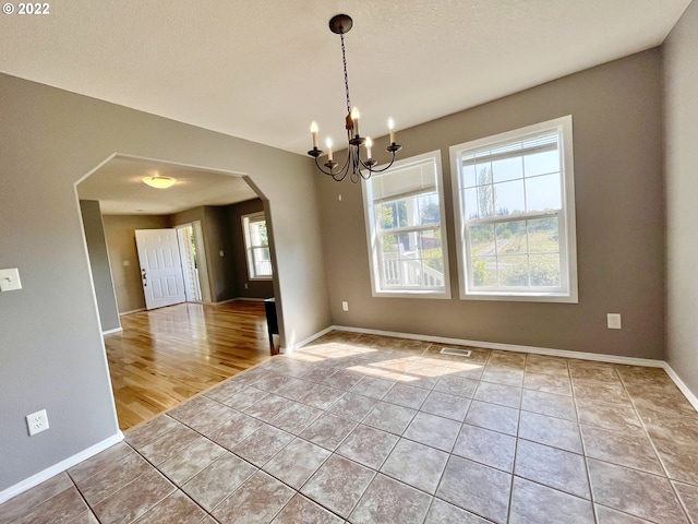 spare room with a chandelier and light wood-type flooring