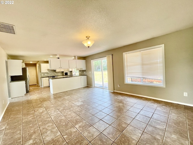 unfurnished living room featuring sink, a textured ceiling, and light tile flooring