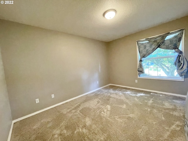 carpeted empty room featuring a textured ceiling