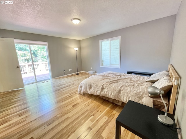 bedroom featuring a textured ceiling, access to exterior, and light hardwood / wood-style flooring