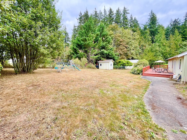 view of yard with a playground, a deck, and a storage shed