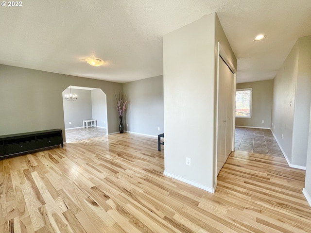 unfurnished room with a notable chandelier and light wood-type flooring