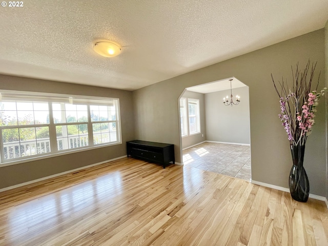 tiled spare room with a notable chandelier and a textured ceiling