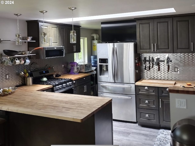 kitchen featuring appliances with stainless steel finishes, butcher block counters, pendant lighting, and backsplash