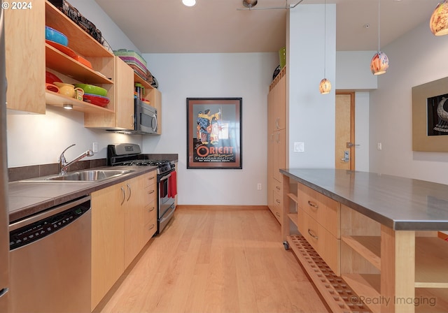 kitchen featuring appliances with stainless steel finishes, hanging light fixtures, light brown cabinetry, and sink