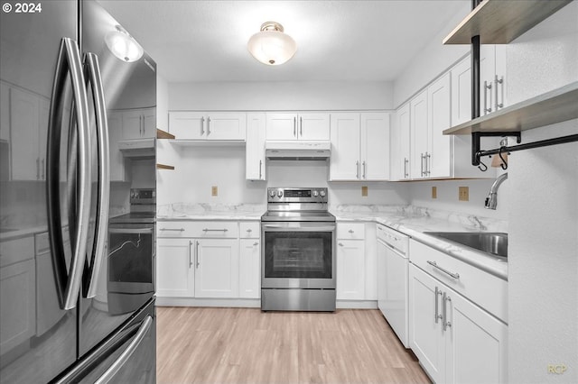 kitchen featuring appliances with stainless steel finishes, light stone counters, sink, white cabinets, and light hardwood / wood-style floors