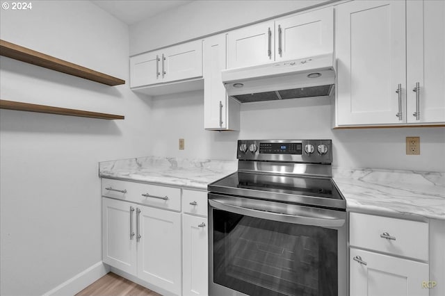 kitchen featuring white cabinets, light wood-type flooring, light stone countertops, and stainless steel range with electric cooktop