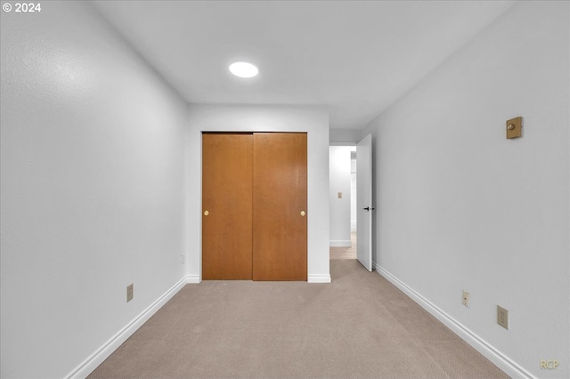 unfurnished bedroom featuring light colored carpet and a closet