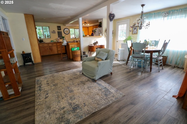 living area featuring an inviting chandelier, radiator heating unit, a wood stove, and dark wood-type flooring