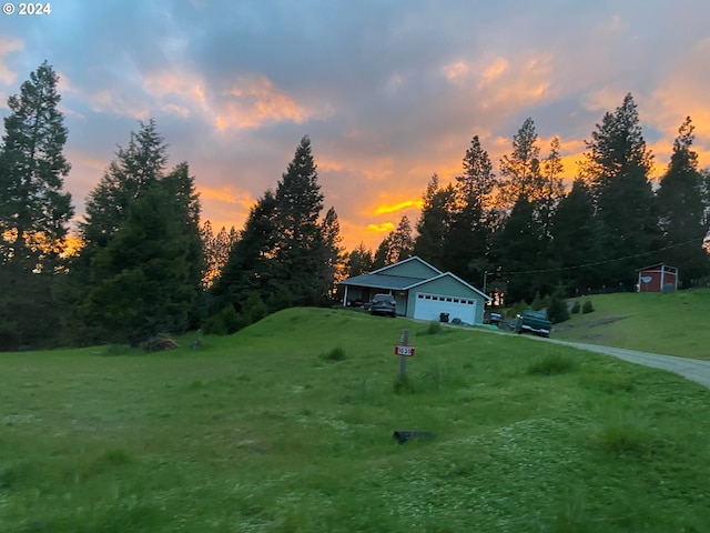 yard at dusk featuring an outbuilding and a garage