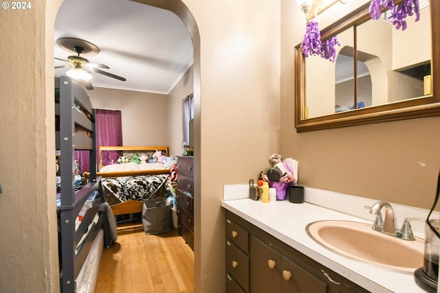 bathroom featuring crown molding, hardwood / wood-style floors, vanity, and ceiling fan