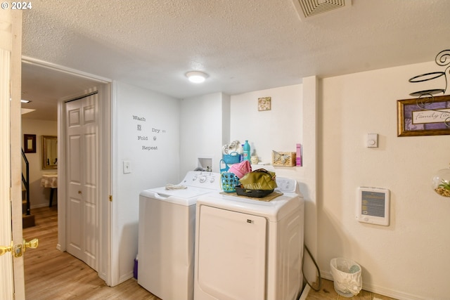 laundry room with separate washer and dryer, heating unit, light hardwood / wood-style floors, and a textured ceiling