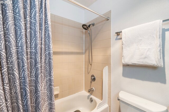 bathroom featuring toilet and shower / tub combo with curtain