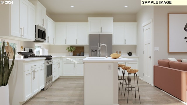 kitchen featuring white cabinetry, light hardwood / wood-style flooring, a kitchen island with sink, a breakfast bar, and appliances with stainless steel finishes