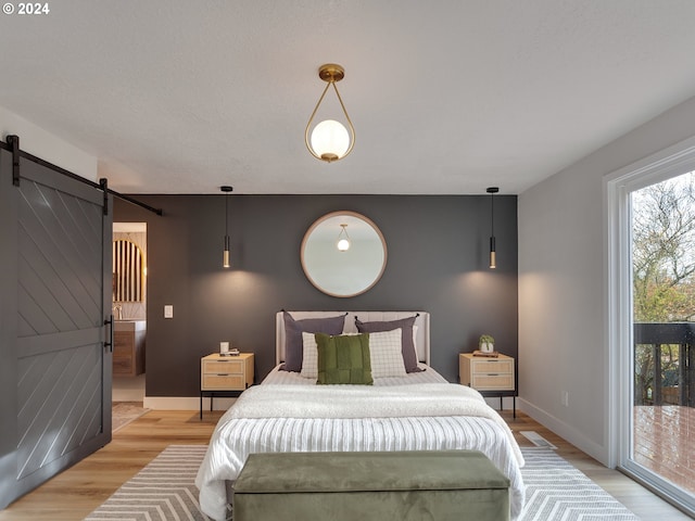 bedroom with access to outside, a barn door, and light hardwood / wood-style flooring