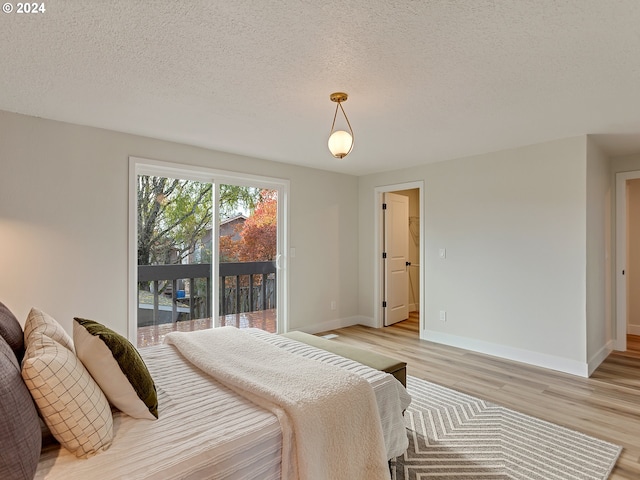 bedroom featuring a textured ceiling, access to outside, and light wood-type flooring