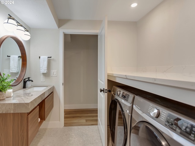 clothes washing area featuring sink, washer and clothes dryer, and light wood-type flooring