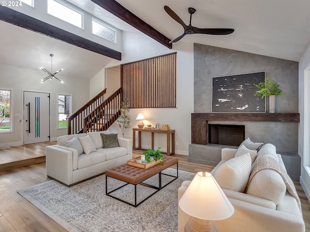 living room with ceiling fan with notable chandelier and light hardwood / wood-style flooring