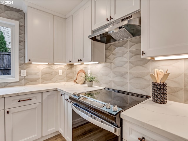 kitchen with tasteful backsplash, white cabinets, light stone countertops, and stainless steel range with electric cooktop