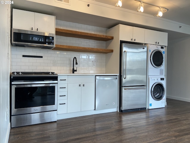 kitchen with dark hardwood / wood-style flooring, white cabinets, stacked washer / drying machine, and appliances with stainless steel finishes