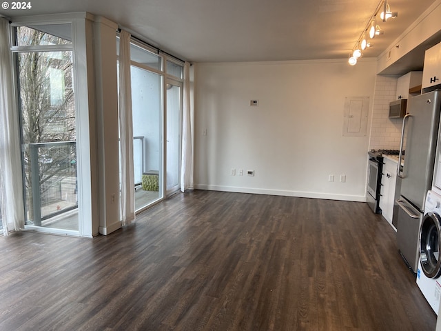 unfurnished living room featuring ornamental molding, electric panel, stacked washer / drying machine, and dark wood-type flooring