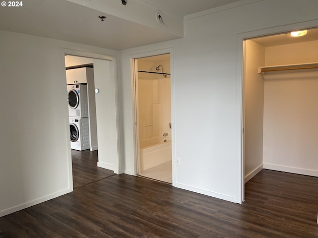 interior space featuring connected bathroom, a spacious closet, dark hardwood / wood-style flooring, stacked washer / drying machine, and a closet