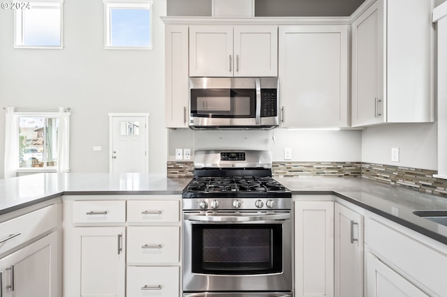 kitchen featuring appliances with stainless steel finishes, white cabinets, tasteful backsplash, and plenty of natural light