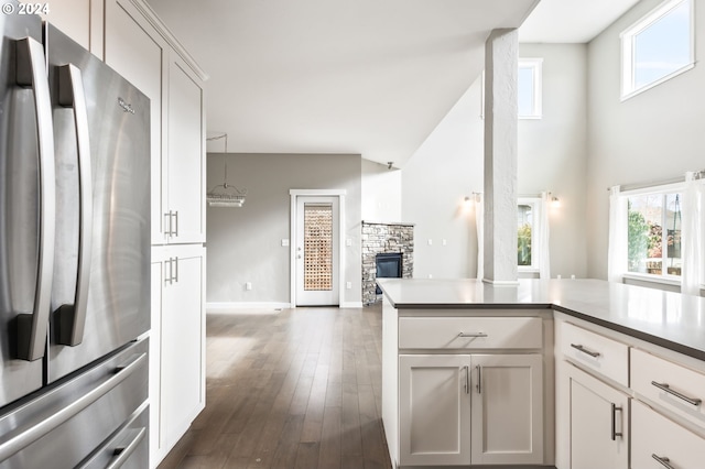 kitchen featuring dark wood-type flooring, stainless steel refrigerator, a fireplace, and white cabinets