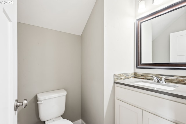 bathroom featuring vanity, decorative backsplash, vaulted ceiling, and toilet