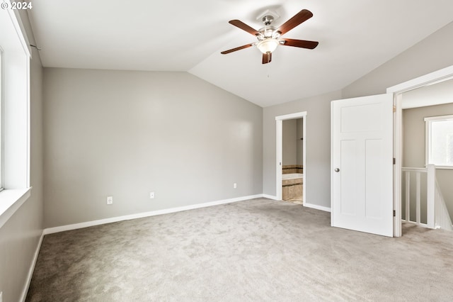 unfurnished bedroom featuring ensuite bath, vaulted ceiling, carpet floors, and ceiling fan