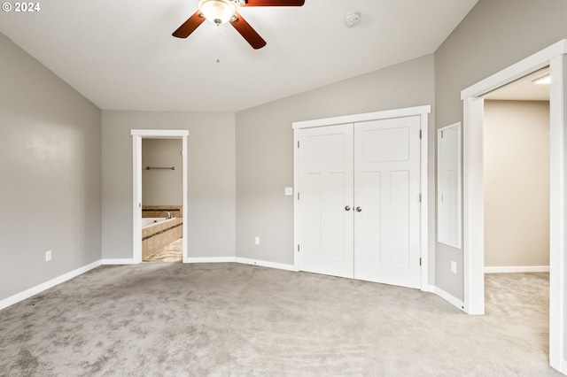 unfurnished bedroom with a closet, ensuite bathroom, light colored carpet, and ceiling fan