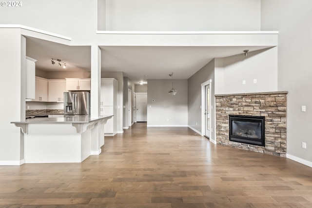 kitchen featuring kitchen peninsula, white cabinets, a breakfast bar area, stainless steel fridge with ice dispenser, and wood-type flooring