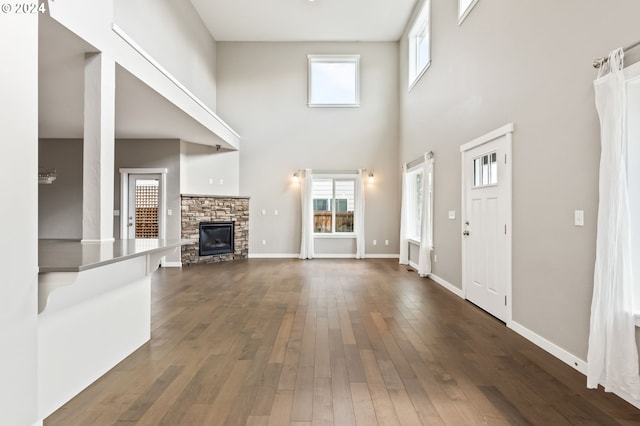 unfurnished living room featuring a fireplace, dark hardwood / wood-style flooring, and a high ceiling