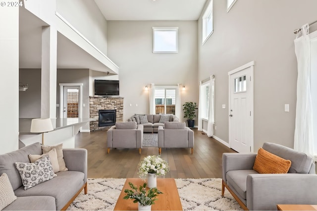 living room with a towering ceiling, hardwood / wood-style flooring, and a healthy amount of sunlight