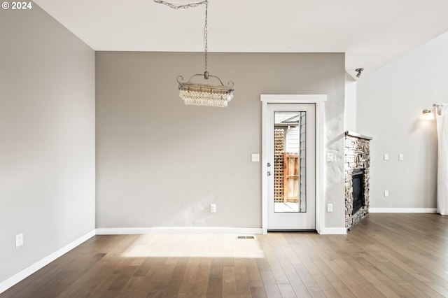 interior space featuring an inviting chandelier, hardwood / wood-style flooring, and a fireplace