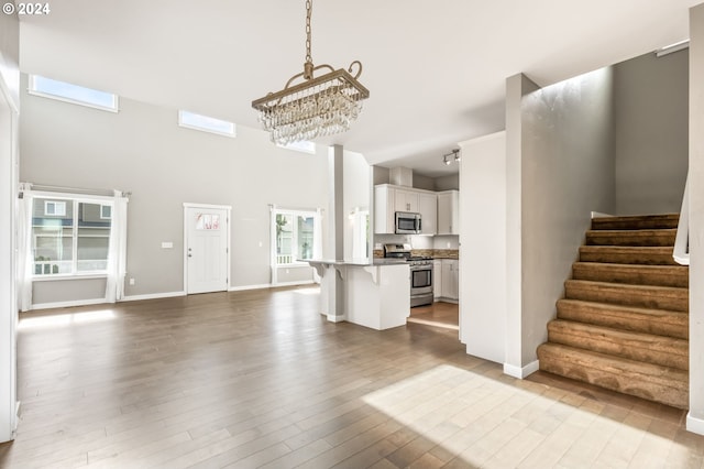 unfurnished living room featuring light hardwood / wood-style flooring, a chandelier, and a high ceiling