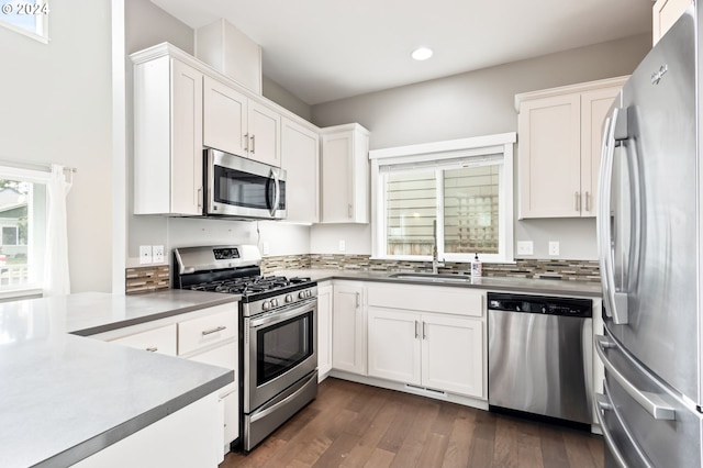 kitchen with dark hardwood / wood-style flooring, appliances with stainless steel finishes, sink, and white cabinets