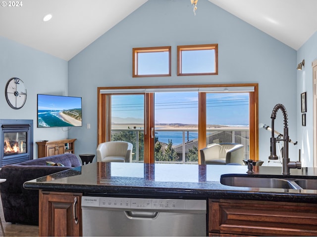 kitchen featuring dishwasher, dark stone countertops, sink, and vaulted ceiling