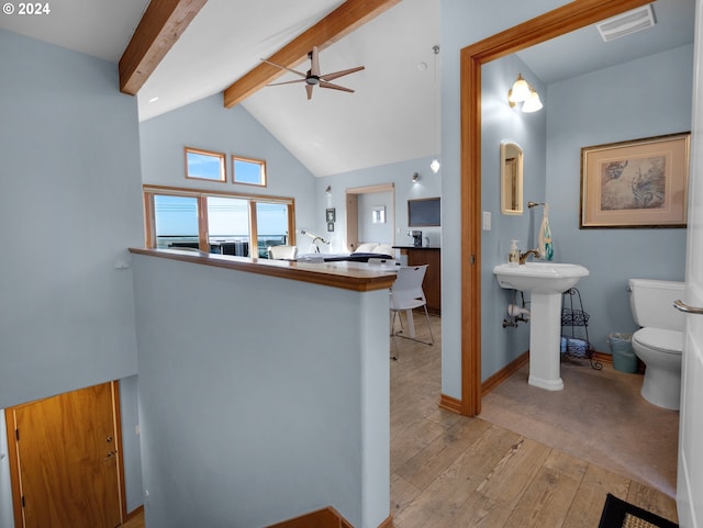 interior space with kitchen peninsula, a kitchen bar, ceiling fan, light hardwood / wood-style flooring, and lofted ceiling with beams