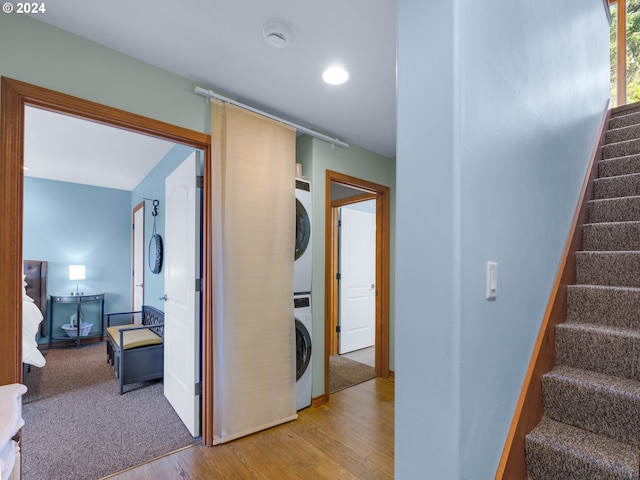 hallway featuring stacked washer and clothes dryer and light hardwood / wood-style flooring