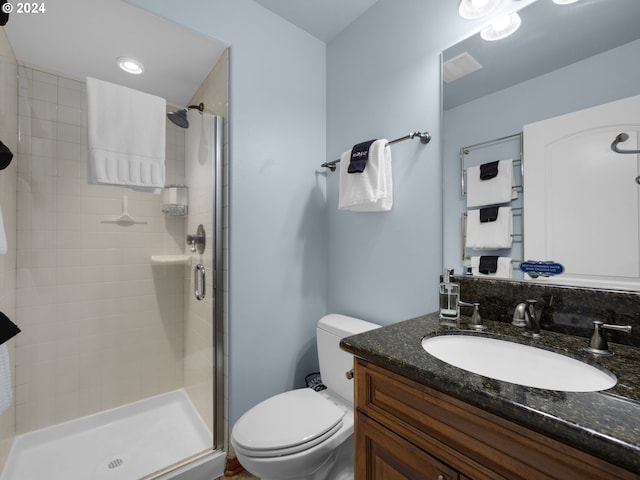 bathroom featuring toilet, vanity, and an enclosed shower