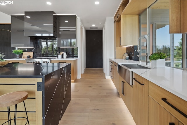 kitchen featuring sink, backsplash, a center island, a kitchen bar, and light wood-type flooring