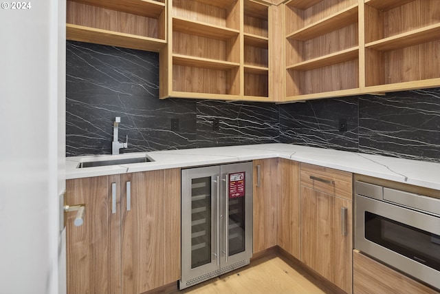 kitchen with sink, tasteful backsplash, stainless steel microwave, beverage cooler, and light stone countertops