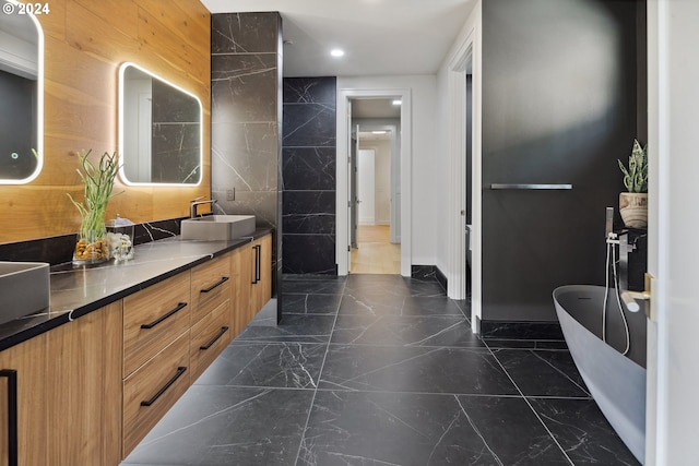 bathroom featuring a bathing tub, tile walls, and vanity