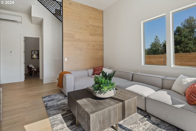 living room featuring hardwood / wood-style flooring, wooden walls, a wall mounted AC, and a high ceiling