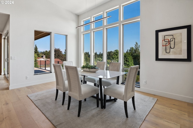 dining space with light hardwood / wood-style floors and a high ceiling