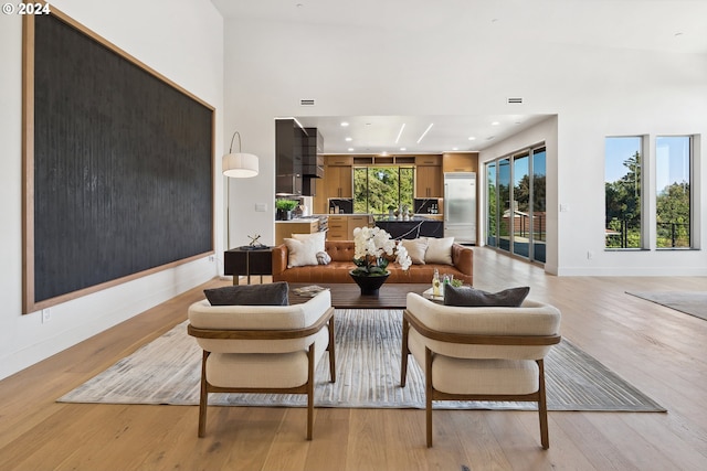 living room with a towering ceiling and light wood-type flooring