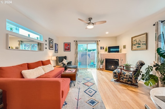 living room featuring a tile fireplace, ceiling fan, hardwood / wood-style floors, and plenty of natural light