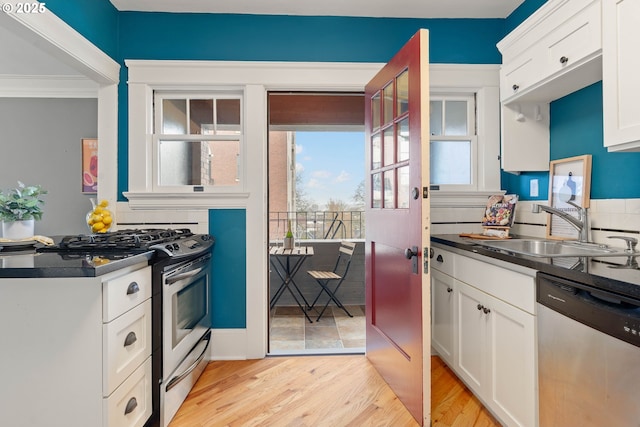 118 NW King Ave Unit 52, Portland, OR 97210 - kitchen with stainless steel dishwasher, a breakfast bar area, white cabinetry, crown molding, and light wood-style flooring